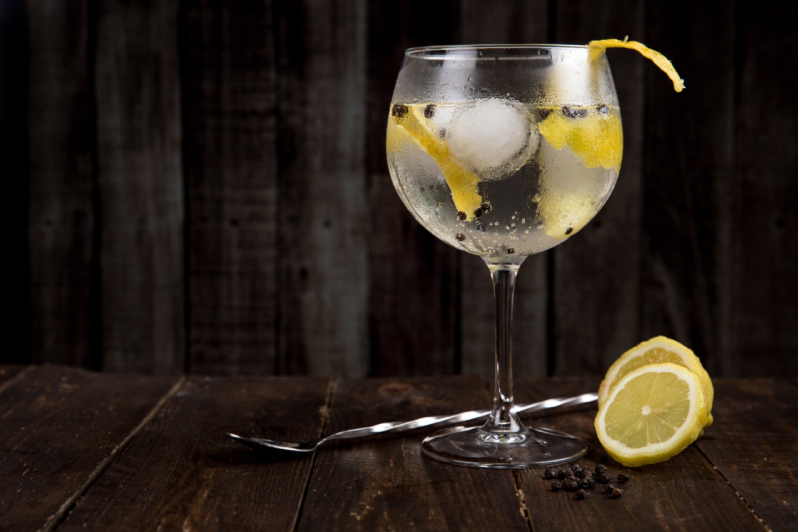 A tall glass of clear soda over ice with a twist of lemon peel